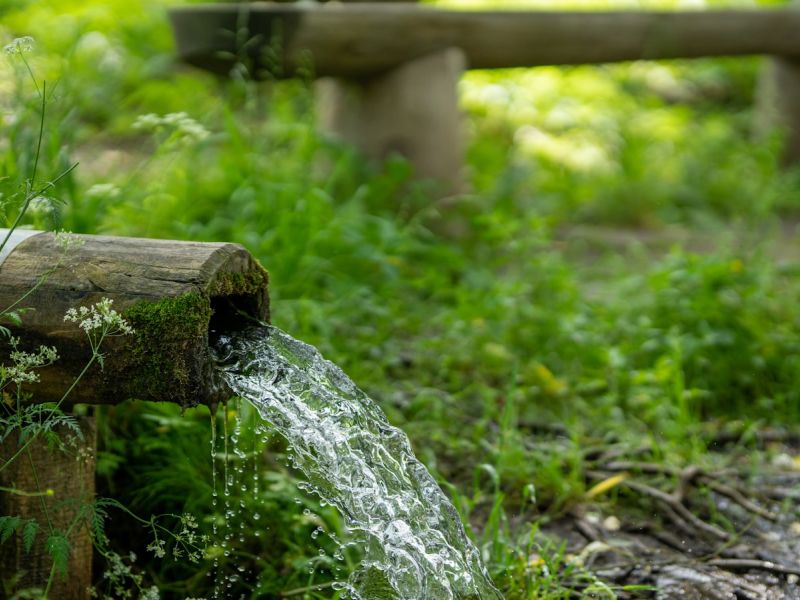 water flowing through bamboo tube during daytime